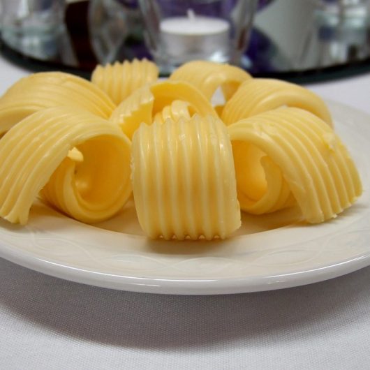 Butter für fluffige Waffeln Butterröllchen auf einem Teller