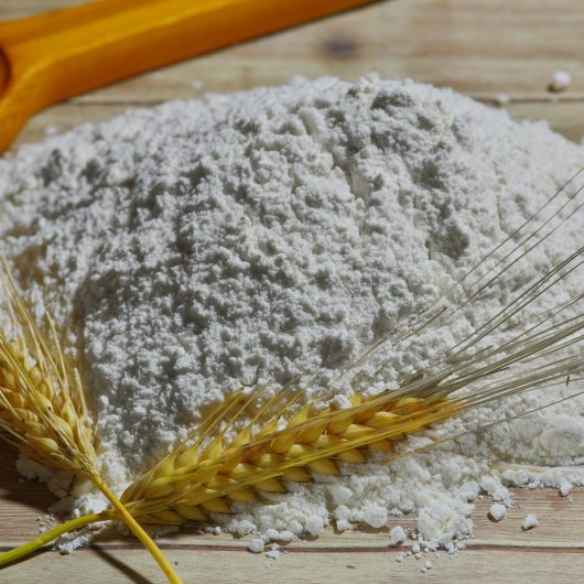 Mehl als Grundzutat für Waffelteig helles Mehl mit Getreide auf einem Holzbrett