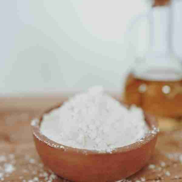 a wooden bowl filled with white powder next to a bottle of honey