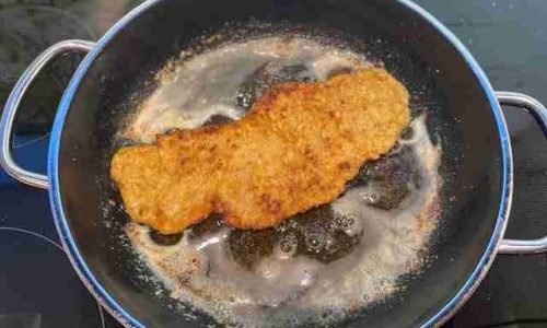 Wiener Schnitzel beim Braten in einer Pfanne